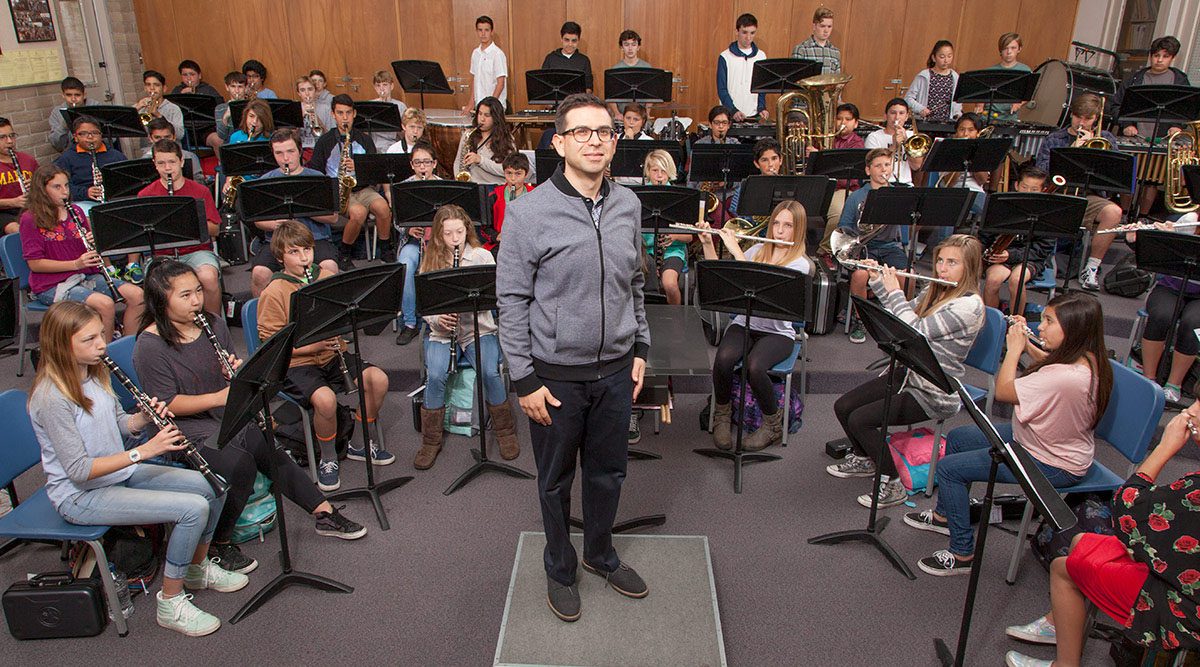 Sala de aula de música no ensino superior, com professor e alunos utilizando instrumentos de sopro