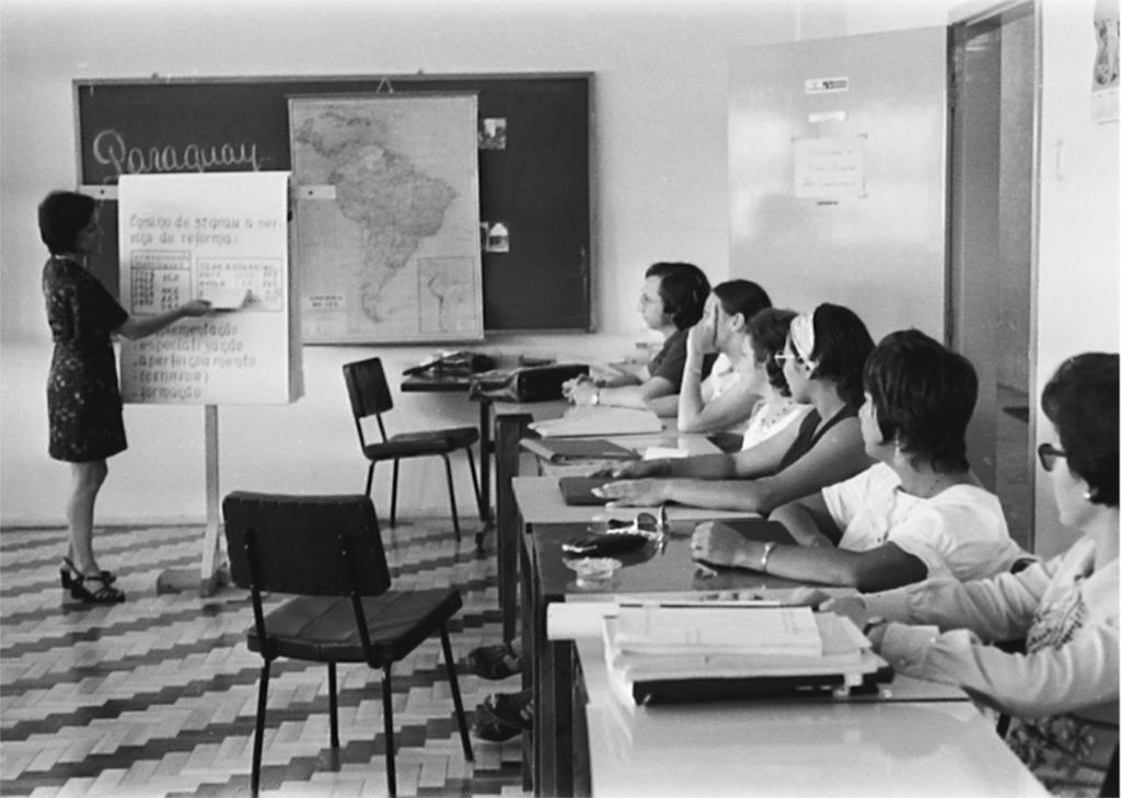 Professora ministra aula a estudantes em sala de aula de escola pública, em orientação horizontal