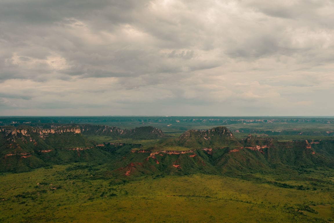 Vista aérea do Cerrado em Mato Grosso, com serras baixas e vegetação esparsa sob céu amplo.
