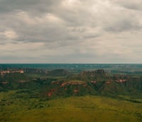 Vista aérea do Cerrado em Mato Grosso, com serras baixas e vegetação esparsa sob céu amplo.