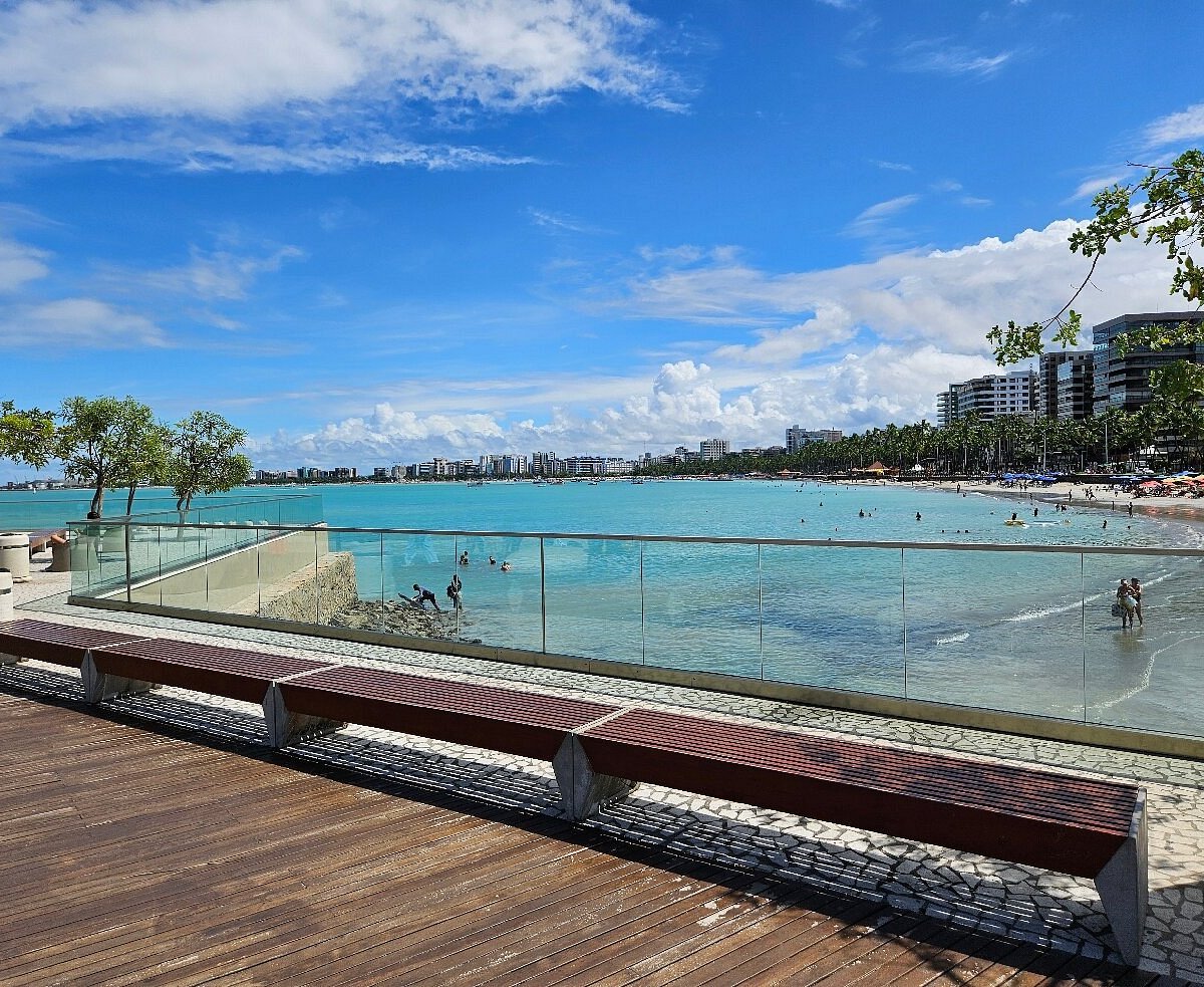 Costa de Maceió na hora dourada, com águas turquesa e skyline urbano