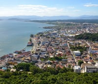 Vista aérea de Laguna SC, mostrando o mar, pontes e casario histórico.