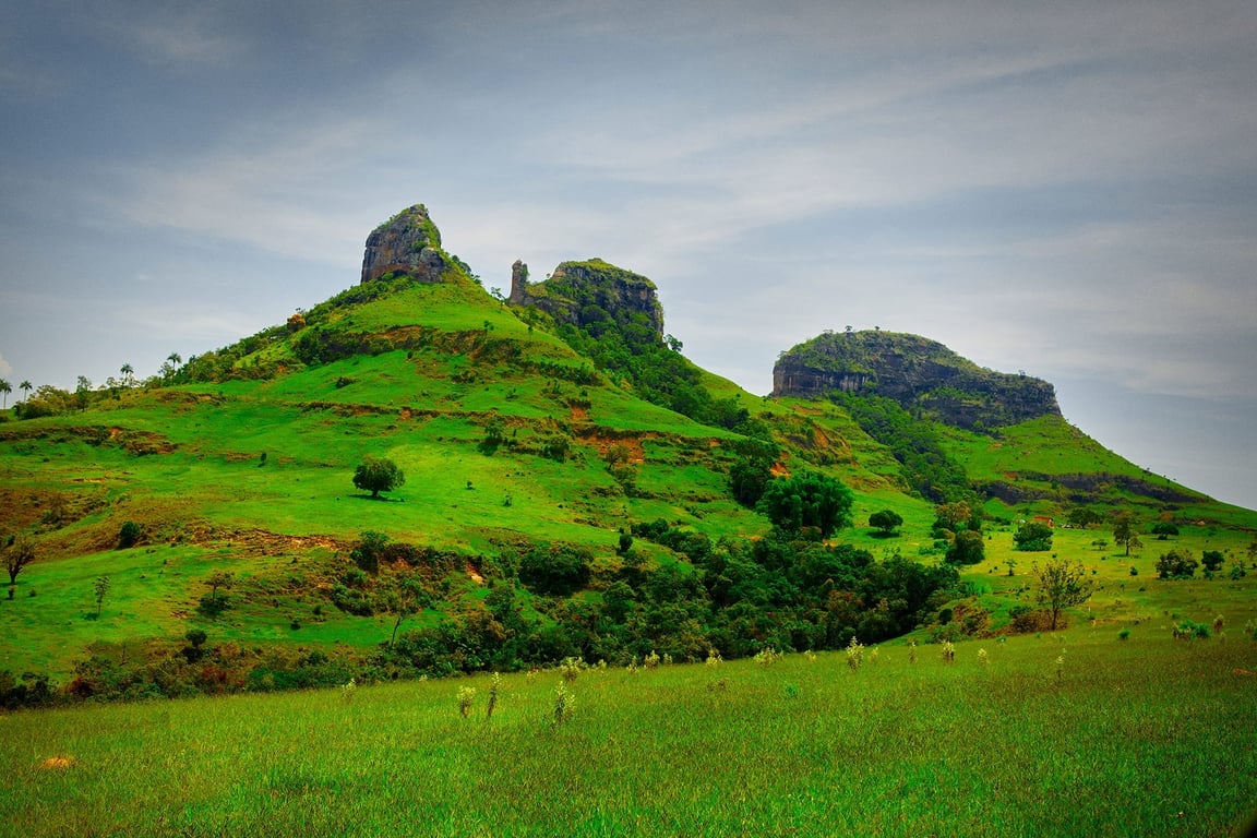 Paisagem da Cuesta de Botucatu ao entardecer, com morros verdes e céu parcialmente nublado