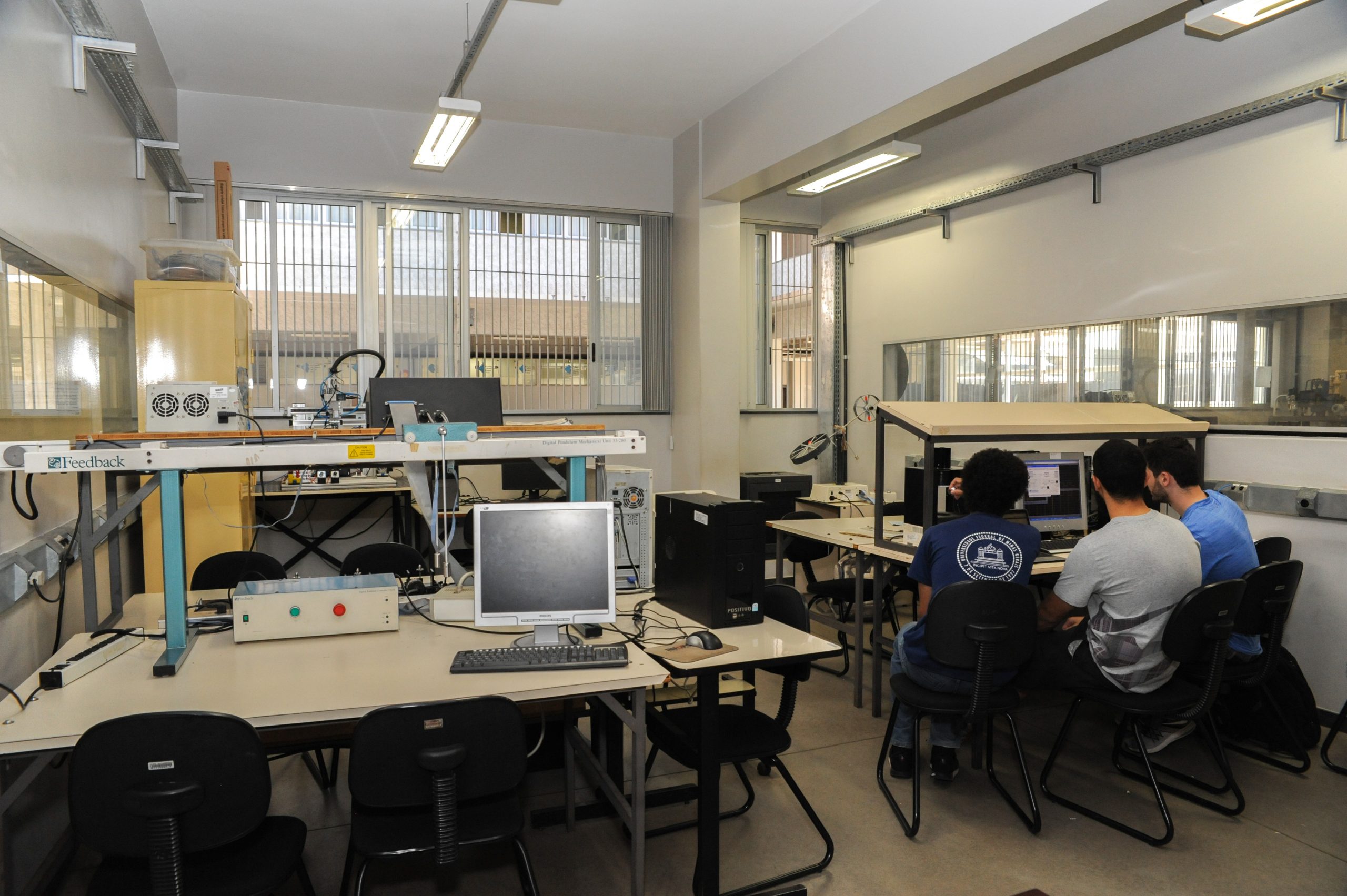 Laboratório acadêmico de automação com estudantes, CLPs, painéis e braços robóticos leves