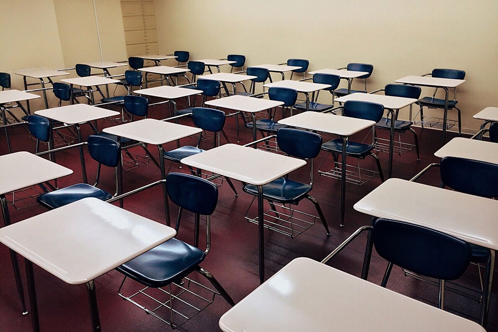 Sala de aula de escola pública, com carteiras vazias e lousa ao fundo