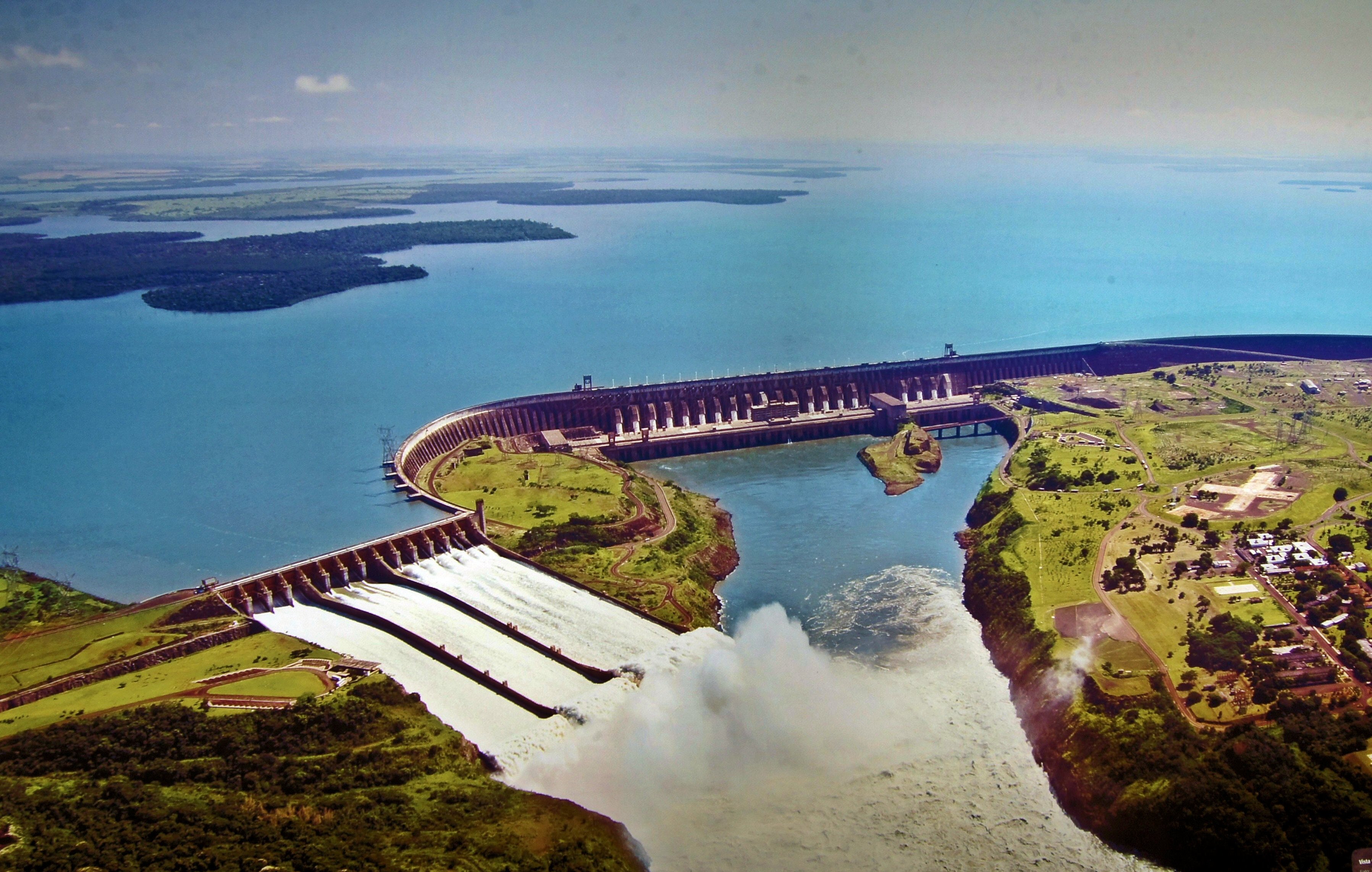 Panorâmica da Usina de Itaipu ao entardecer, com reservatório e vertedouro