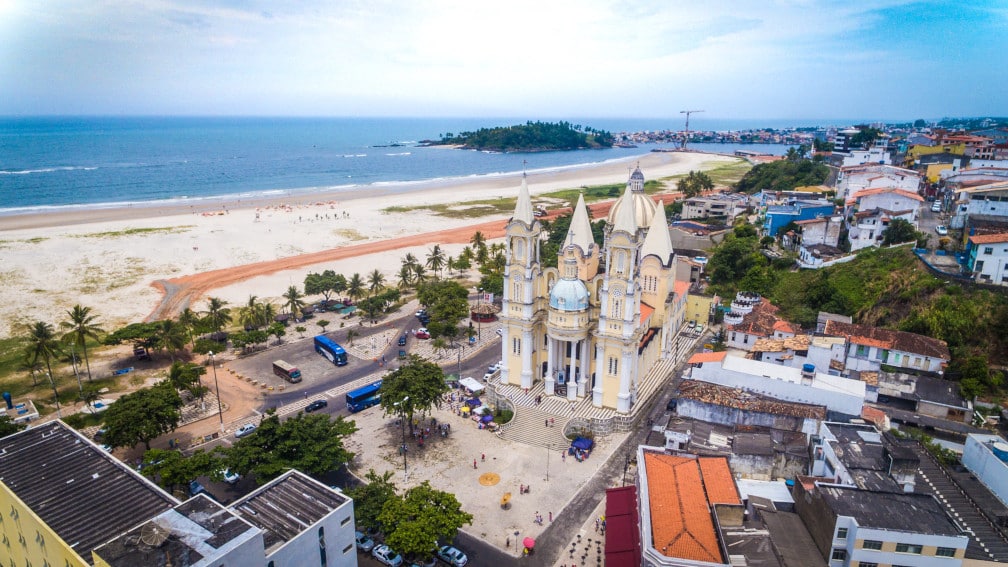 Vista aérea da orla de Ilhéus, com praia, mar e área urbana ao fundo