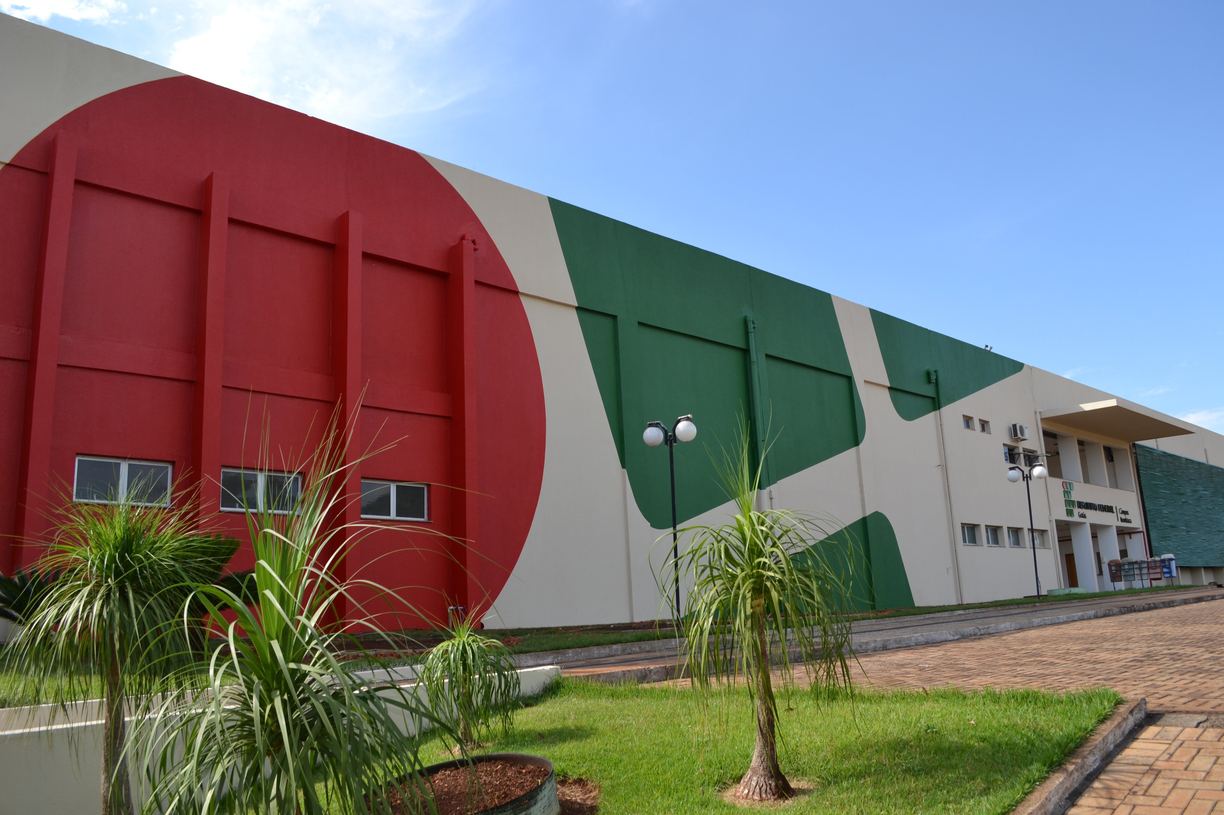 Fachada de um campus do Instituto Federal em dia ensolarado, com jardins e arquitetura moderna