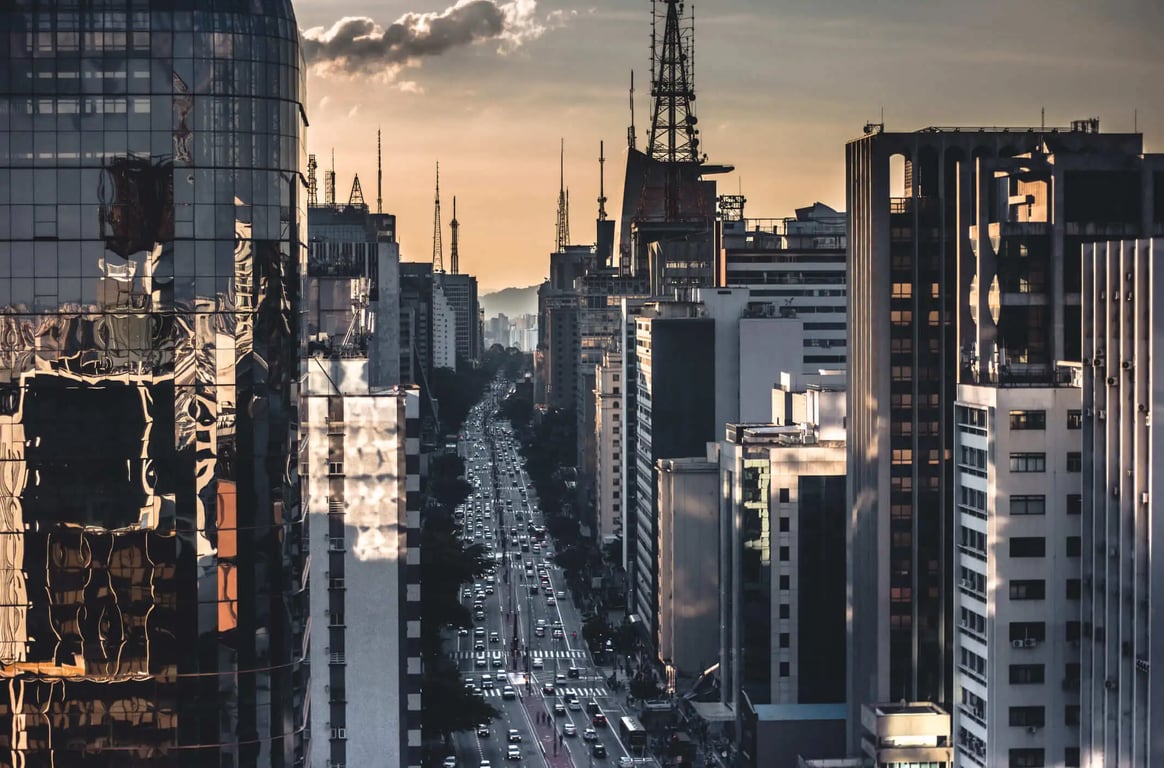 Horizonte de São Paulo ao entardecer, com prédios e avenida movimentada