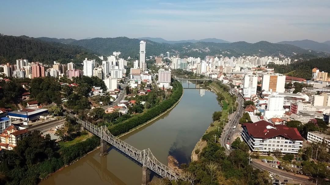 Panorama de Blumenau ao entardecer, com o rio Itajaí-Açu e arquitetura local
