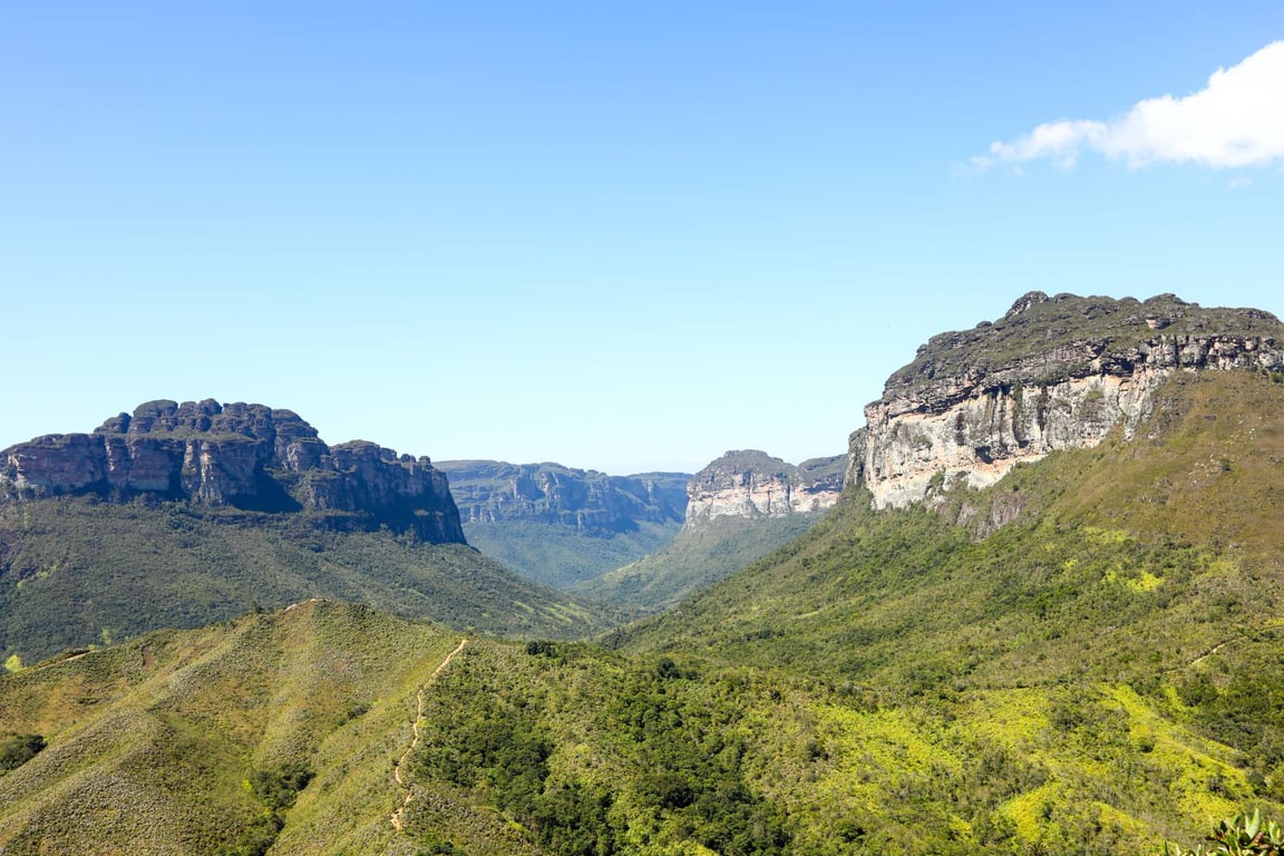 Paisagem ampla da Chapada Diamantina, com montanhas e vegetação exuberante sob céu claro