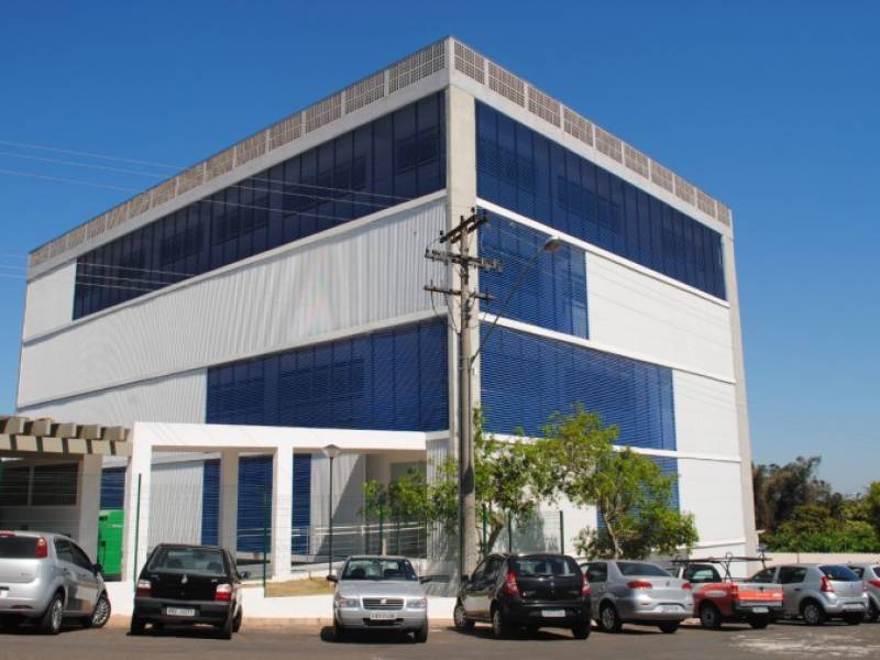 Campus da UNESP em Botucatu, prédio moderno cercado por áreas verdes, em dia claro