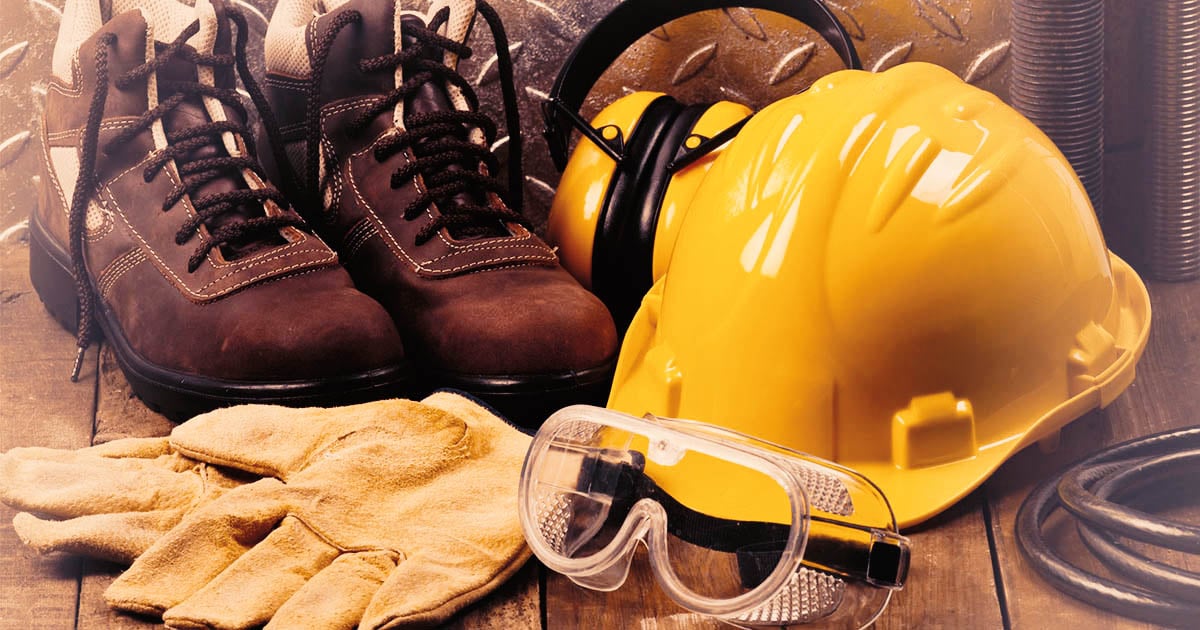 Equipamentos de proteção individual sobre bancada de madeira (capacete, óculos, luvas e botas)