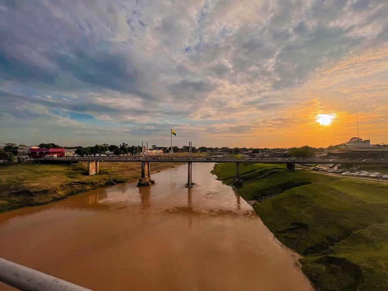 Vista aérea de Rio Branco ao pôr do sol, com o Rio Acre e a paisagem urbana ao fundo