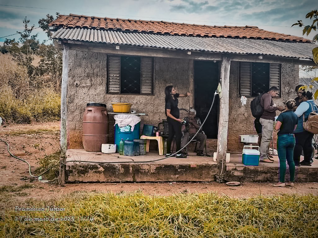 Agente comunitário de saúde em visita domiciliar, conversando com moradora na porta de casa