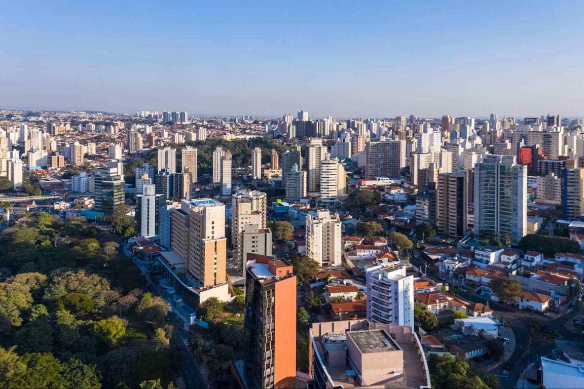 Vista panorâmica de Campinas com prédios e áreas verdes sob céu claro
