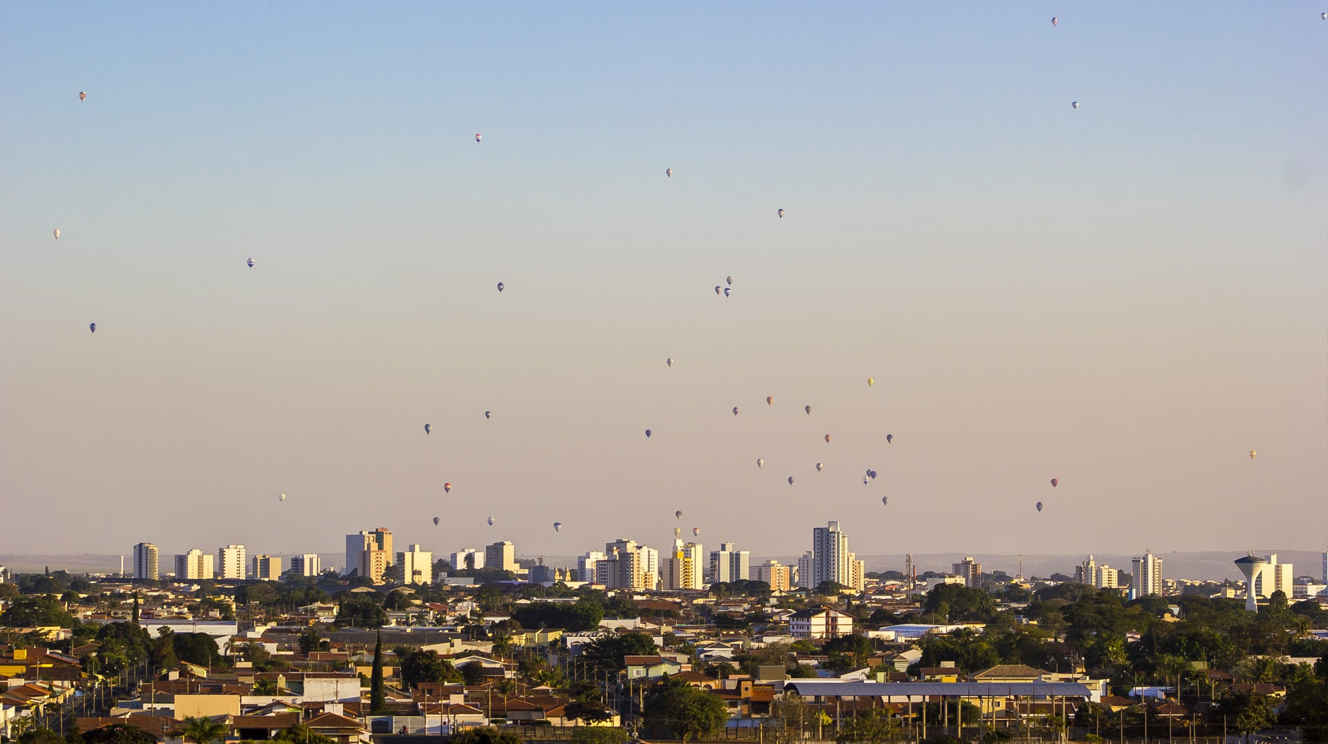 Vista aérea urbana com balões multicoloridos em céu claro