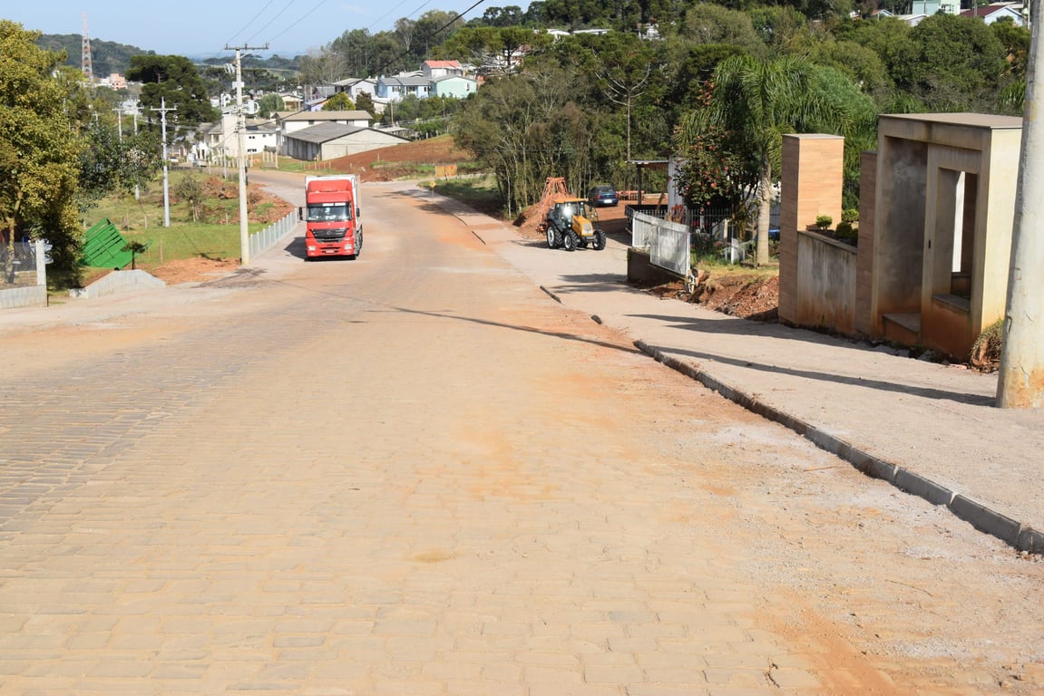 Rua central de pequena cidade serrana no RS, com casas baixas e vegetação; clima ameno de serra