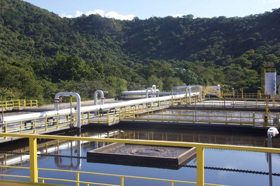 Estação de tratamento de água com tubulações e tanques, cenário industrial em área natural