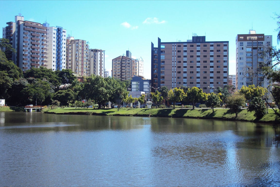 Paisagem urbana de Viçosa, com lago em primeiro plano refletindo prédios ao fundo
