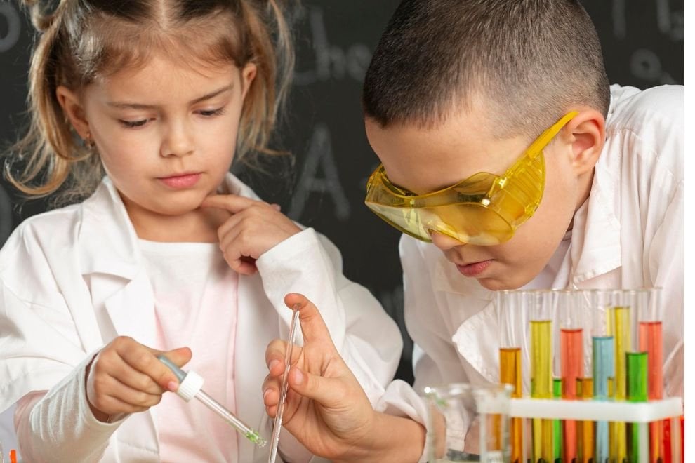 Aula prática de Química em laboratório escolar, com jalecos, óculos de proteção e vidrarias