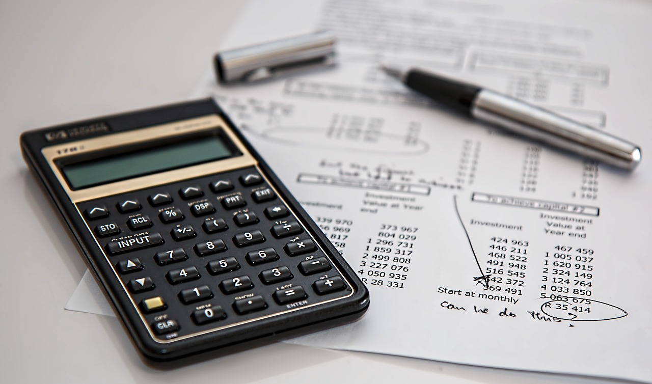 Mesa de trabalho com calculadora e documentos, em ambiente institucional