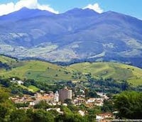 Vista aérea de Paraisópolis MG cercada por montanhas e vegetação, típica do Sul de Minas.