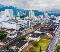 Vista aérea de Jaraguá do Sul SC, com morros verdes e área urbana ao fundo.