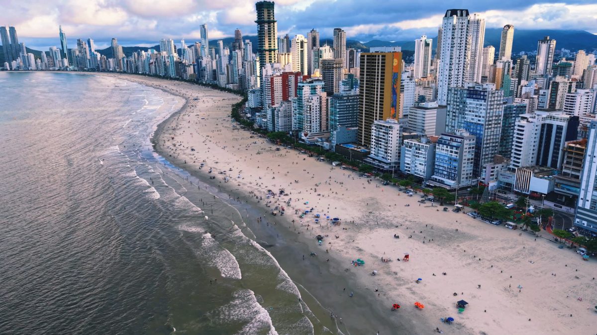 Vista aérea de Balneário Camboriú ao entardecer, com praia e arranha-céus à beira-mar