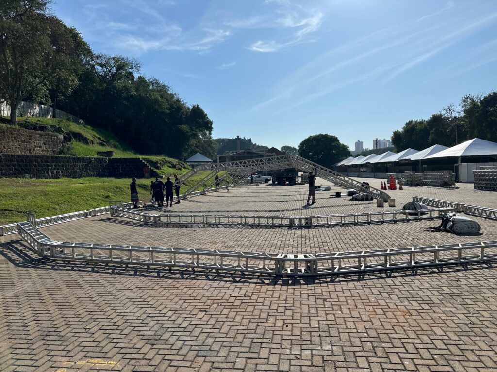 Montagem de estrutura de evento, com treliças e iluminação cênica em área aberta