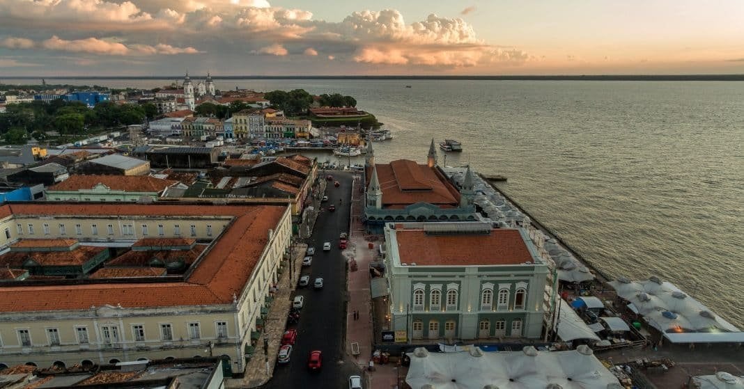 Vista aérea de Belém do Pará ao entardecer, com o rio Guamá e o skyline da cidade