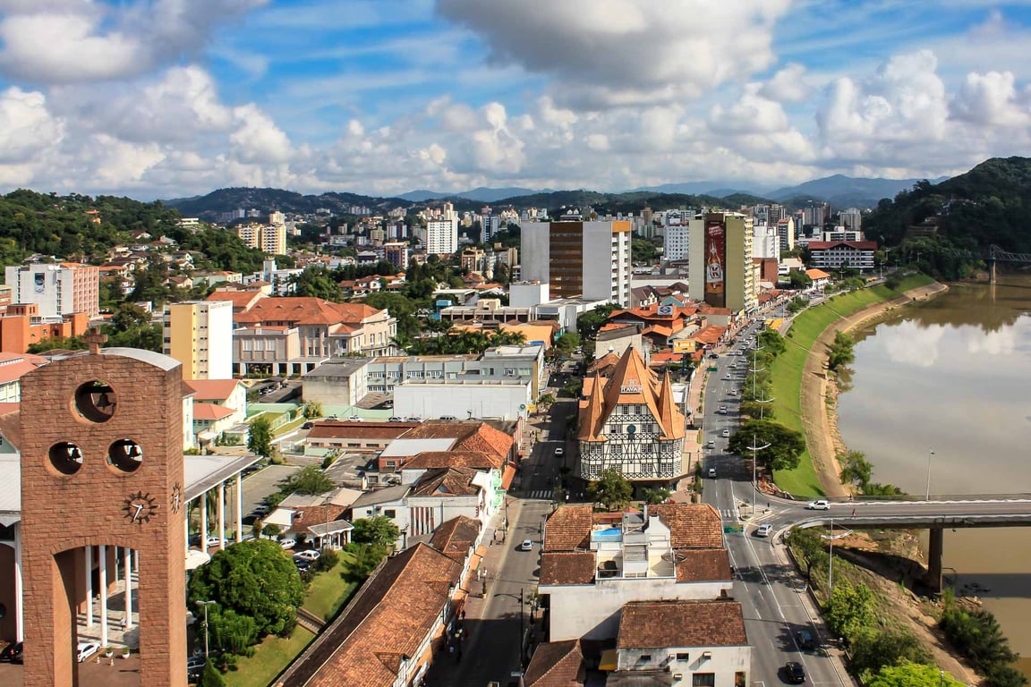 Vista aérea de Blumenau ao entardecer, com o Rio Itajaí-Açu e o centro da cidade