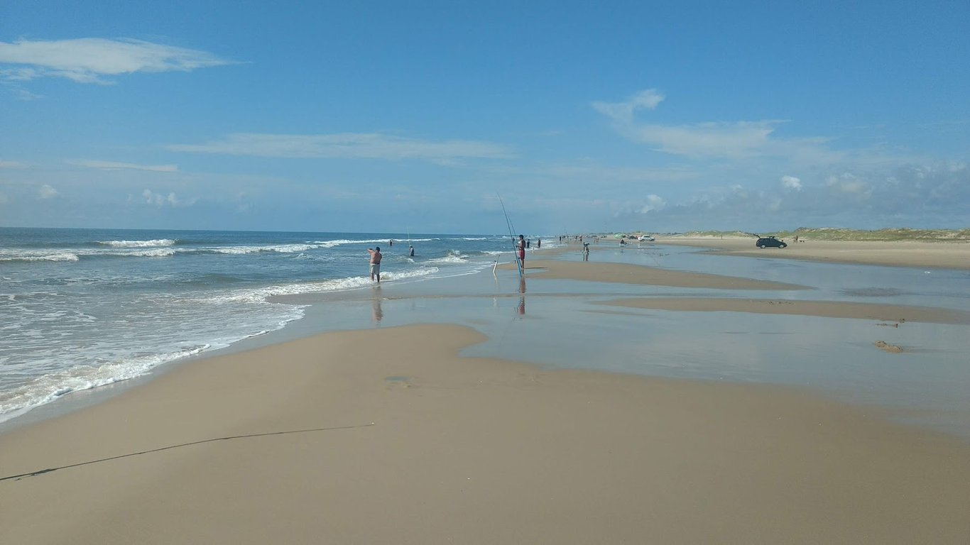 Praia de Quintão, em Palmares do Sul, com mar calmo e céu azul em dia claro