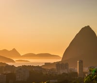 Panorâmica do Rio de Janeiro ao pôr do sol, com o Pão de Açúcar e a Baía de Guanabara ao fundo
