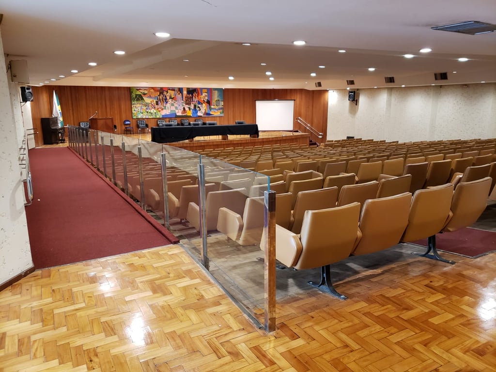 Auditório universitário com poltronas, iluminação suave e palco ao fundo