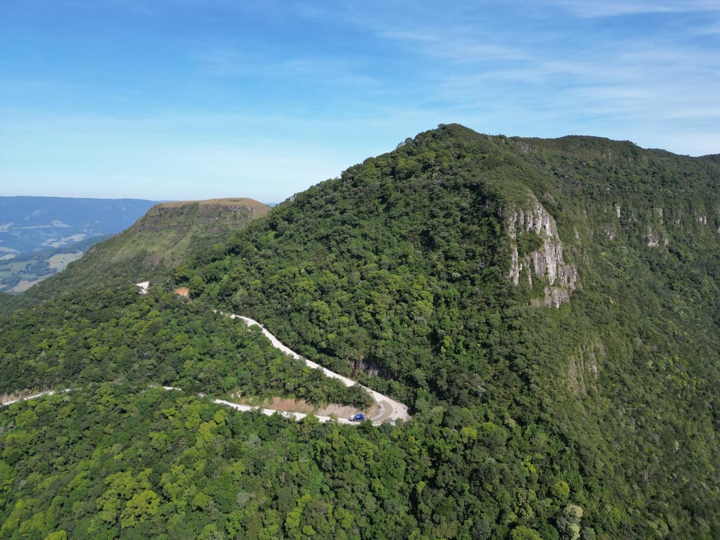 Estrada rural em região serrana, remetendo ao deslocamento e à logística do transporte escolar no interior