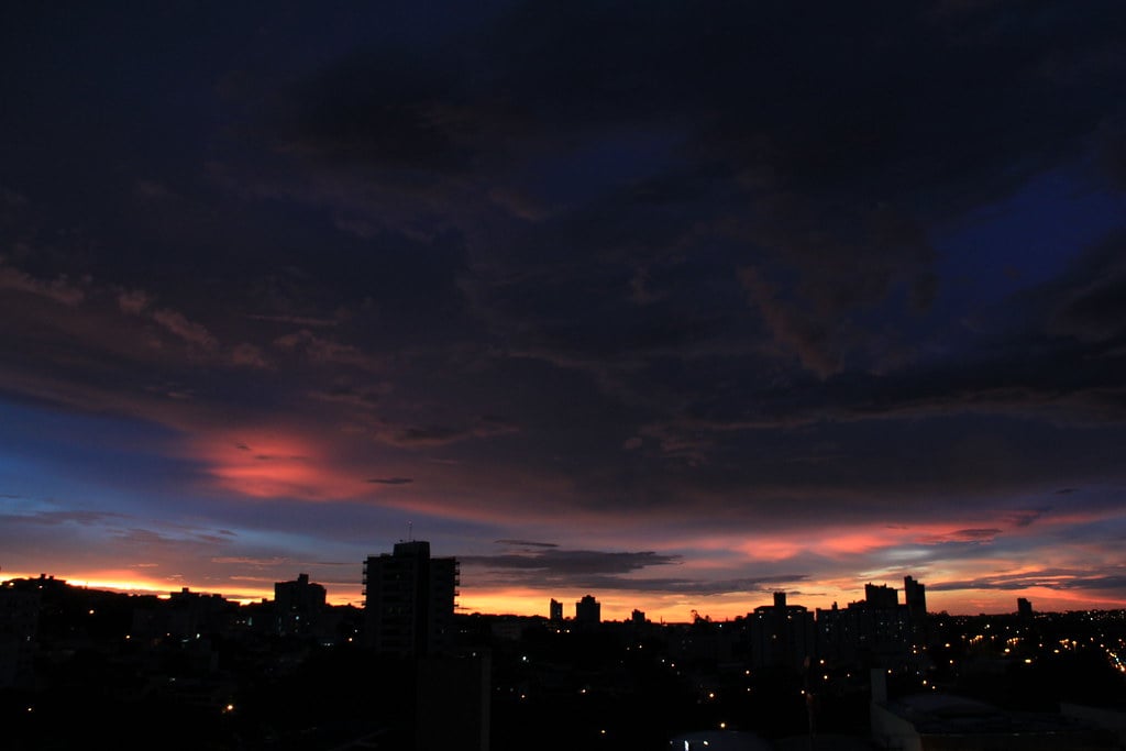 Skyline de Presidente Prudente ao pôr do sol, com edifícios iluminados e céu alaranjado