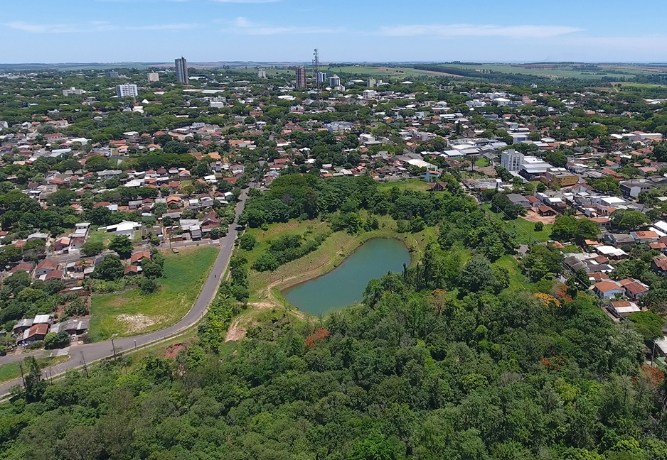 Vista aérea do centro de Nova Esperança PR, com áreas urbanas, vegetação e lago ao centro