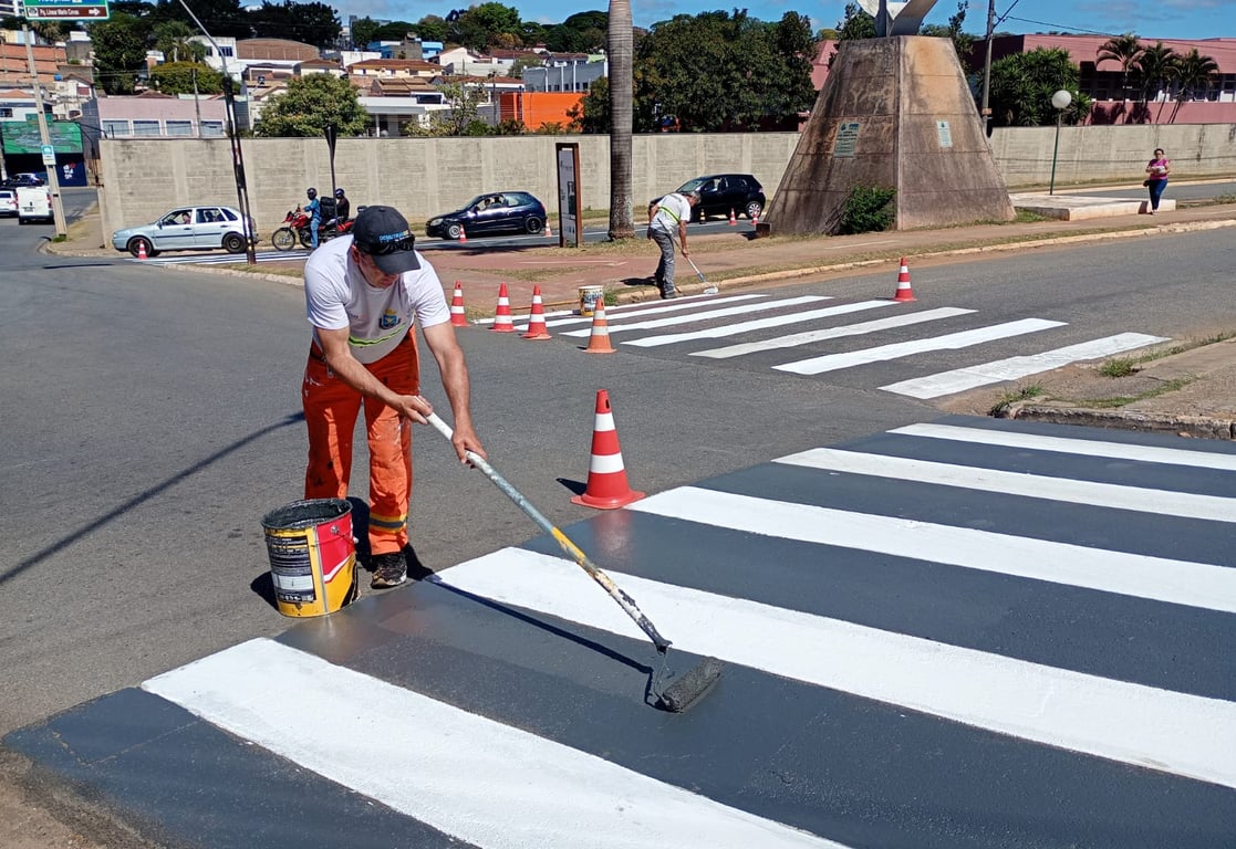 Equipe de manutenção municipal pintando faixas e limpando vias