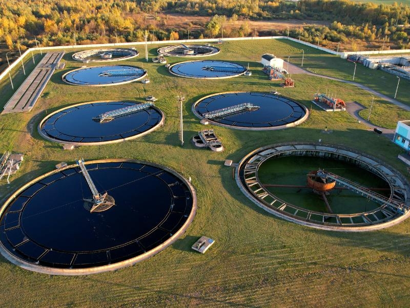 Estação de tratamento de água com tanques de sedimentação, cercada por vegetação