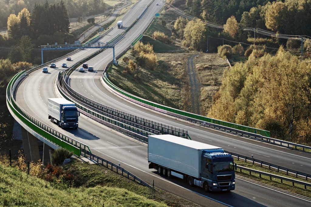 Rodovia com caminhões ao entardecer, ilustrando mobilidade e segurança viária