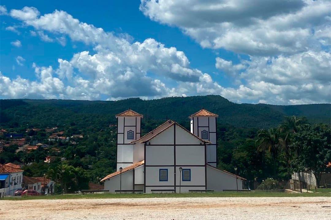 Cerrado goiano e paisagem urbana do interior de Goiás, com morros ao fundo e céu azul