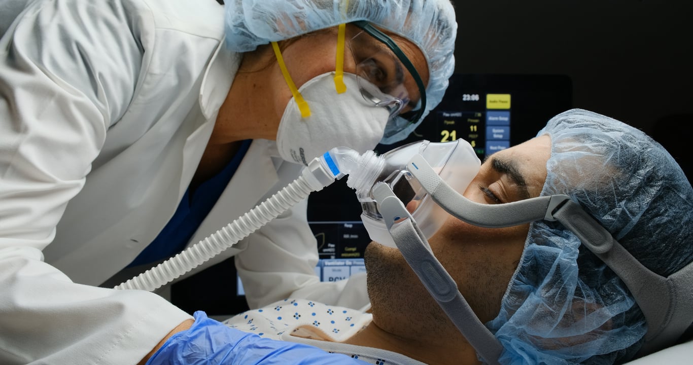 Profissional de saúde ajustando equipamento em UTI com paciente adulto