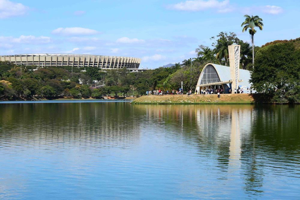 Vista da Lagoa da Pampulha com conjunto arquitetônico ao fundo, ao entardecer