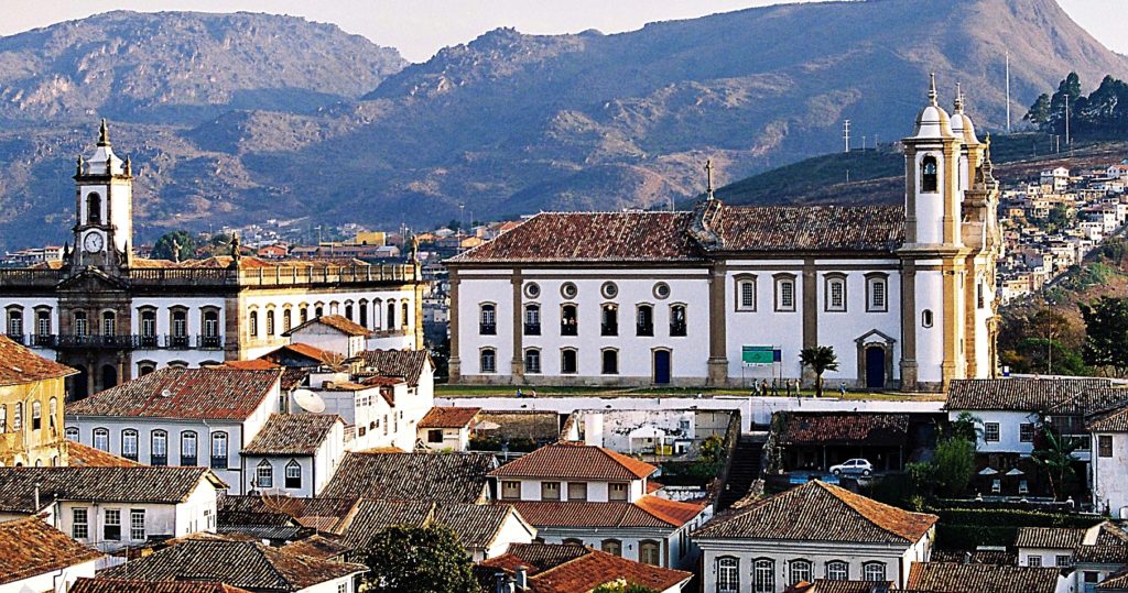 Cidade histórica de Minas com casario e morros ao fundo ao entardecer