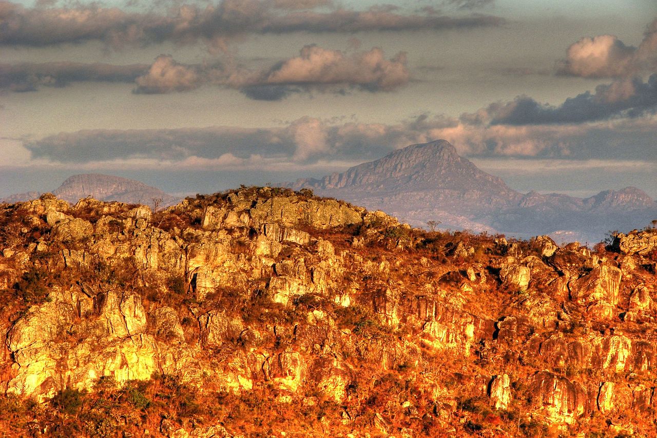 Paisagem serrana em Minas Gerais, com morros e vegetação de cerrado, céu azul e horizonte amplo
