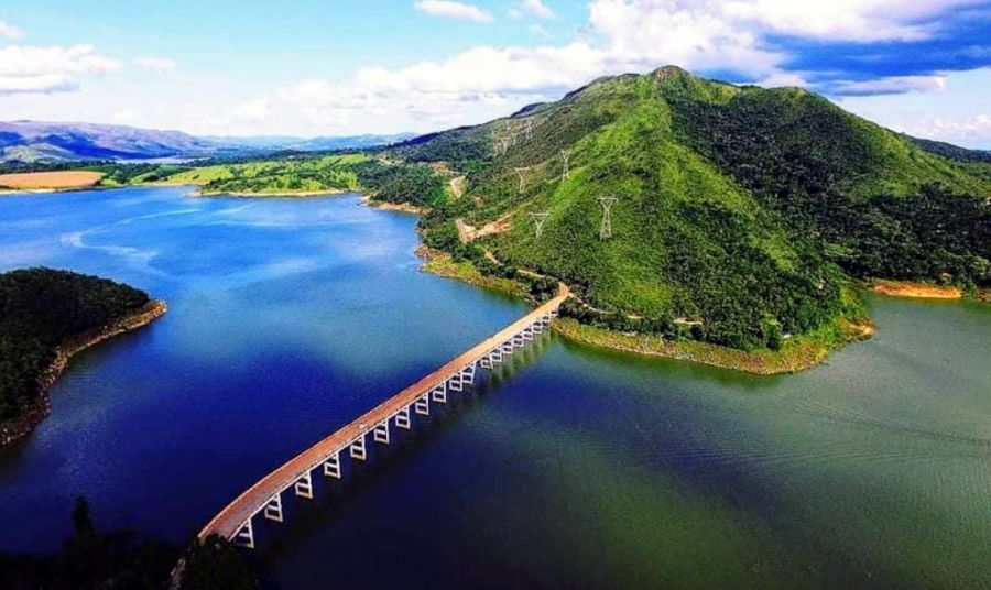 Lago de Furnas ao entardecer, com montanhas ao fundo e ponte, em composição horizontal