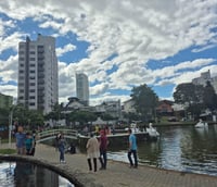Vista panorâmica do centro de Lages, com prédios e pessoas ao redor de um lago