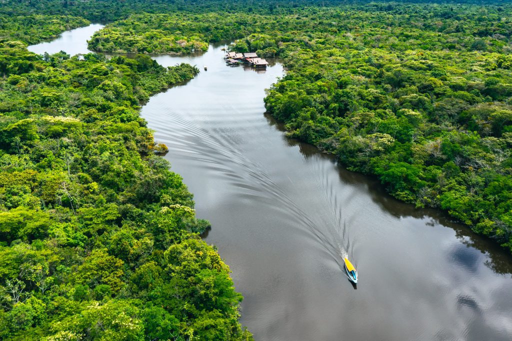 Vista aérea do rio Tarauacá serpenteando pela densa floresta amazônica no Acre, Brasil. A luz do final da tarde ilumina a cena tranquilamente.
