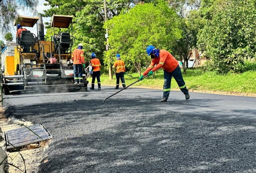 Trabalhadores da construção civil executando obra pública de calçamento, com EPIs